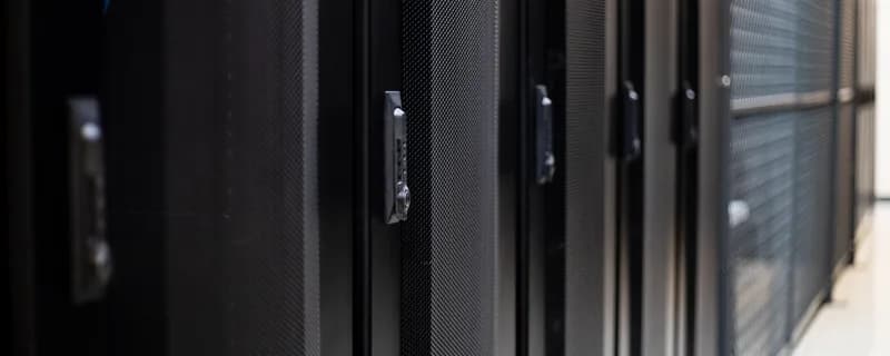 Row of black server rack doors with locking handles in a tym2 data hall